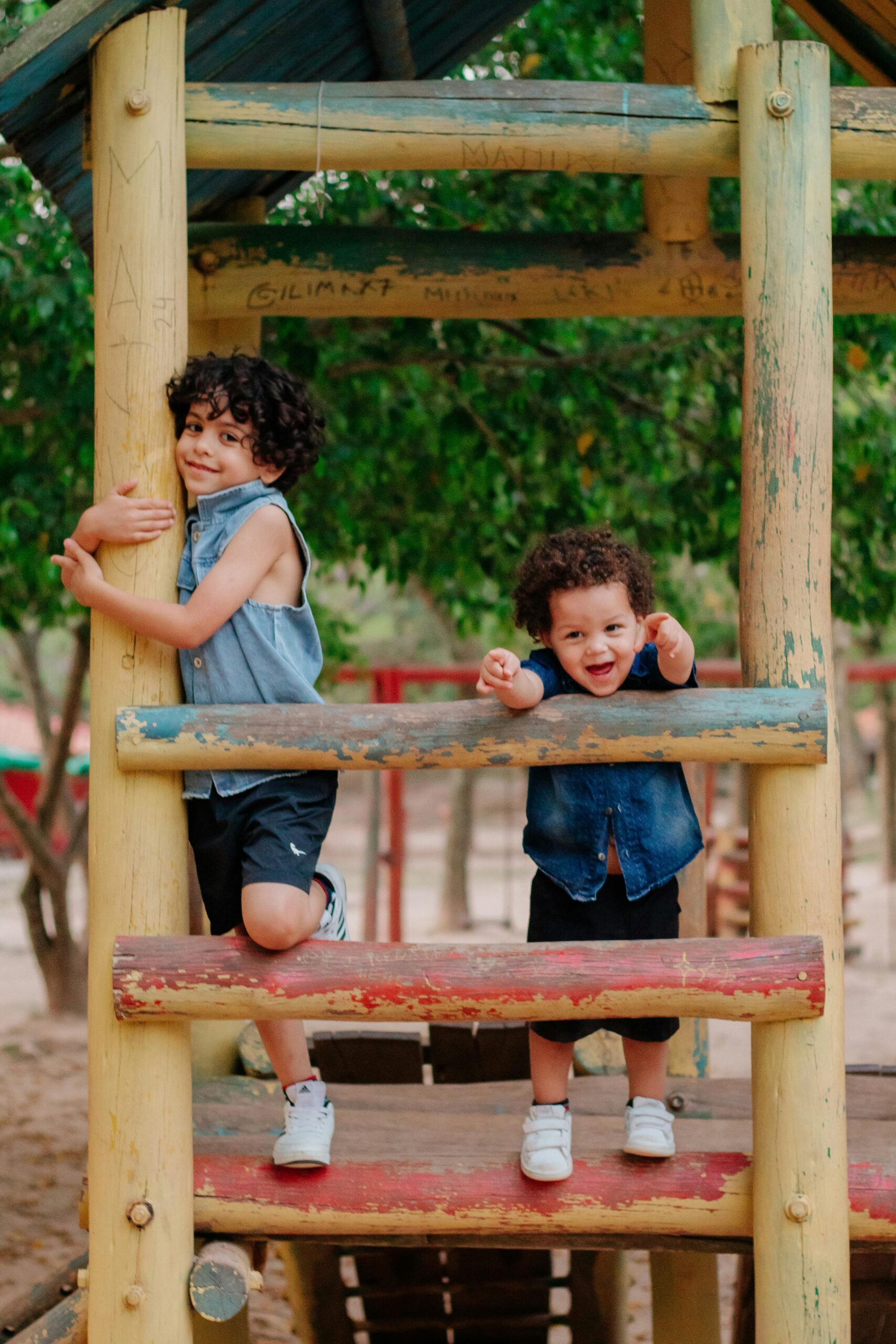 Two young children enjoy climbing and playing outdoors on vibrant playground equipment.